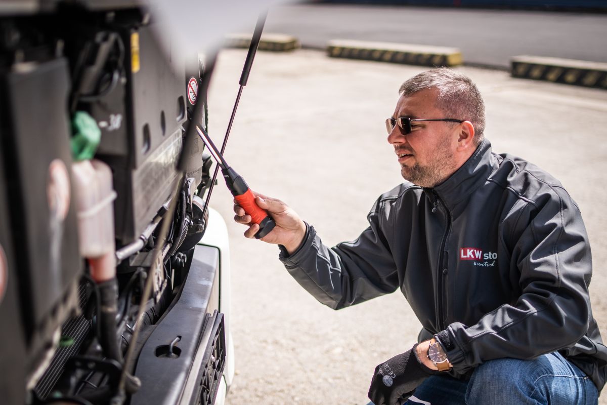 LKW Store-os szakértő a felbillentett fülkéjű teherautó motorterét vizsgálja