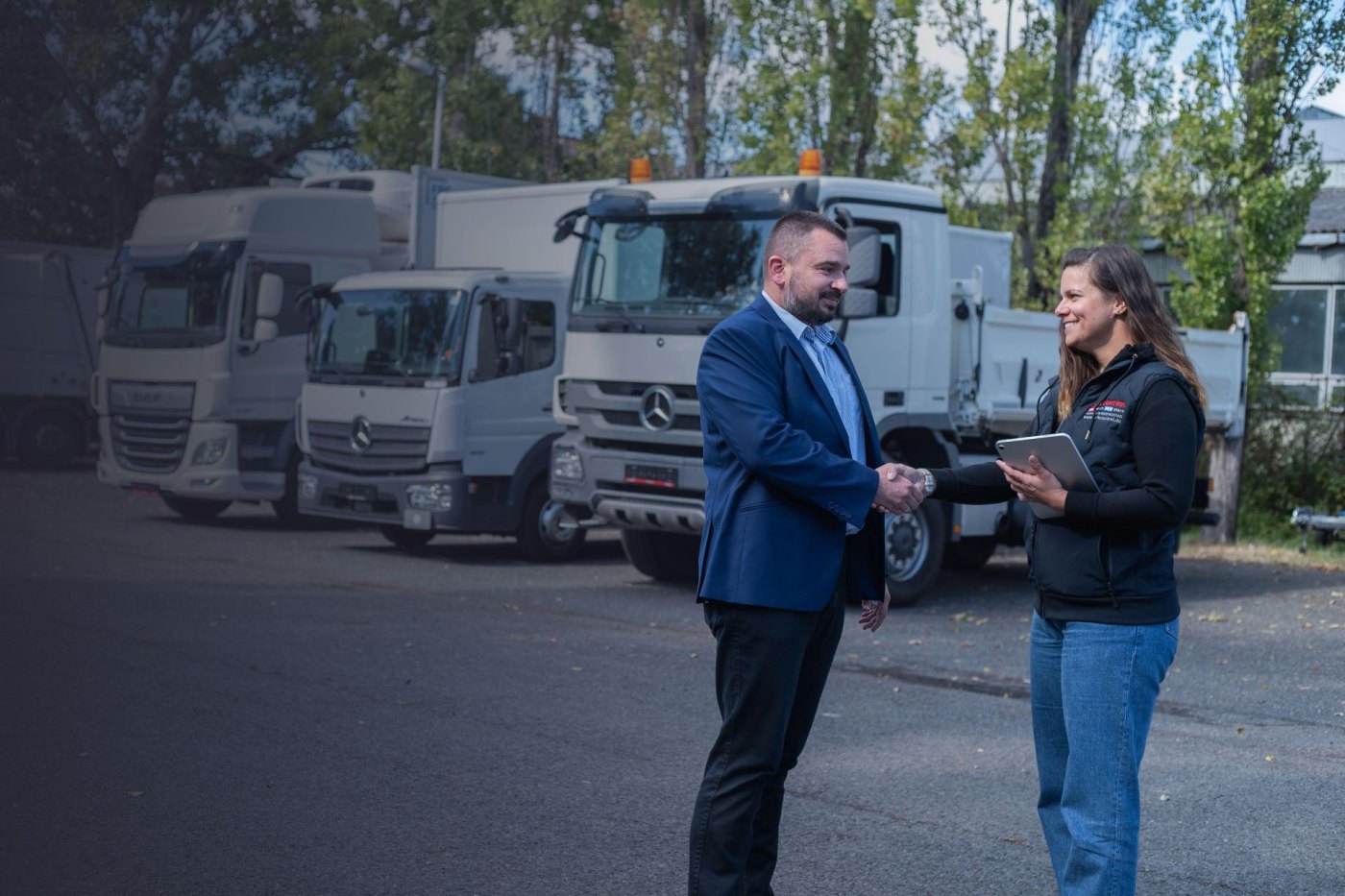Kézfogás az LKW Store soproni telephelyén, a háttérben a járműsor